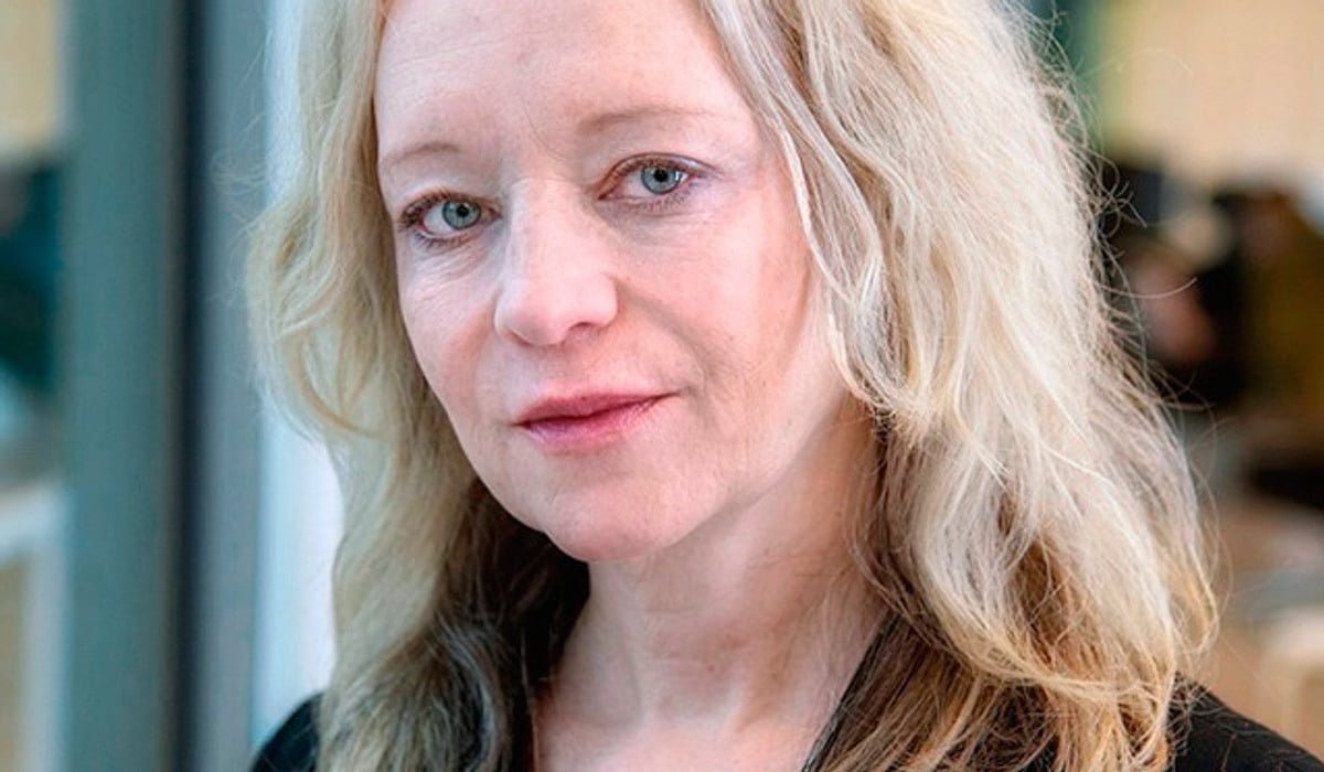 En kvinna med blont hår och svart skjorta.