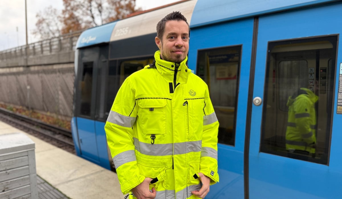 En man står framför ett blått tåg.