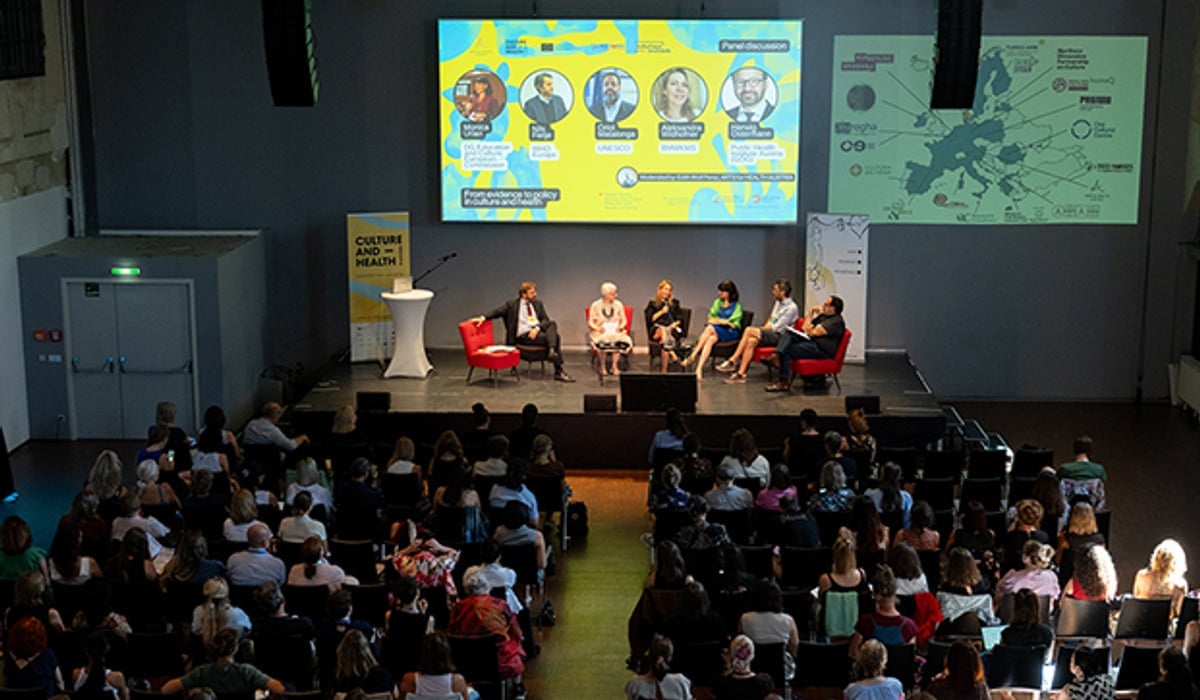 Panel på scen framför stor publik.