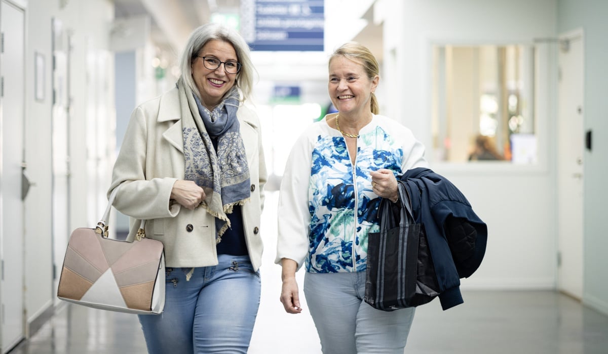 Några leende kvinnor går i en sjukhuskorridor.