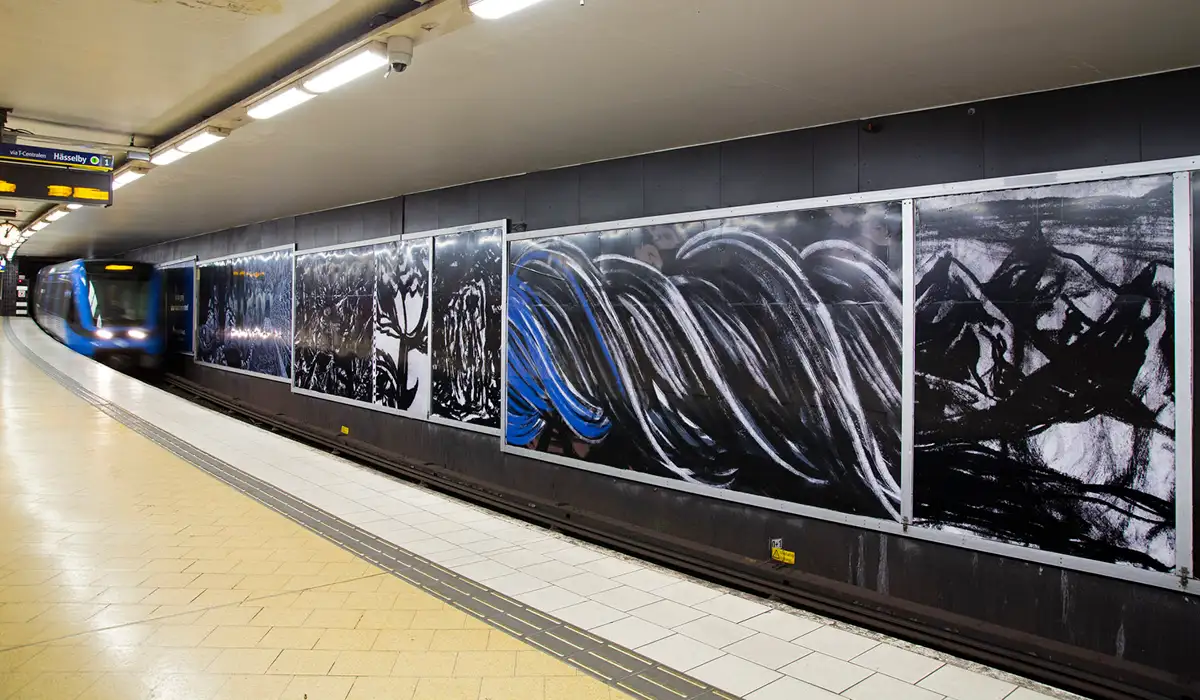 Tåg på väg in på Slussens tunnelbanestation. I förgrunden Rogers kraftfulla teckningar på konsttavlorna.