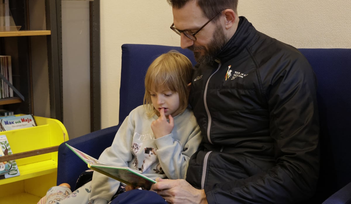 En pappa och en dotter sitter och läser på bibliotek