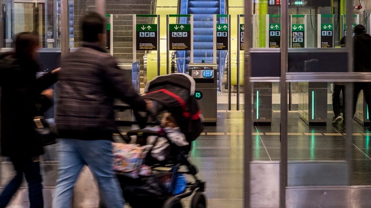 En familj med barnvagn går in på stationen