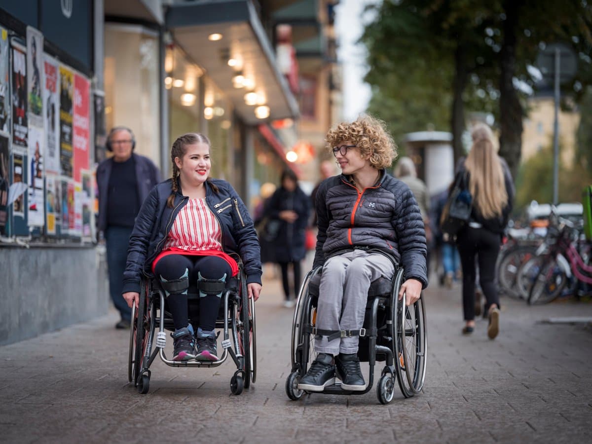 Två personer i rullstol samtalar med varandra medans de tar sig genom en gågata vid Odenplan