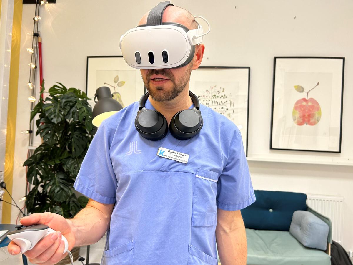 Porträtt av Daniel Kemppi, VR-pedagog som står med VR-headset på sig iförd sjukhuskläder.