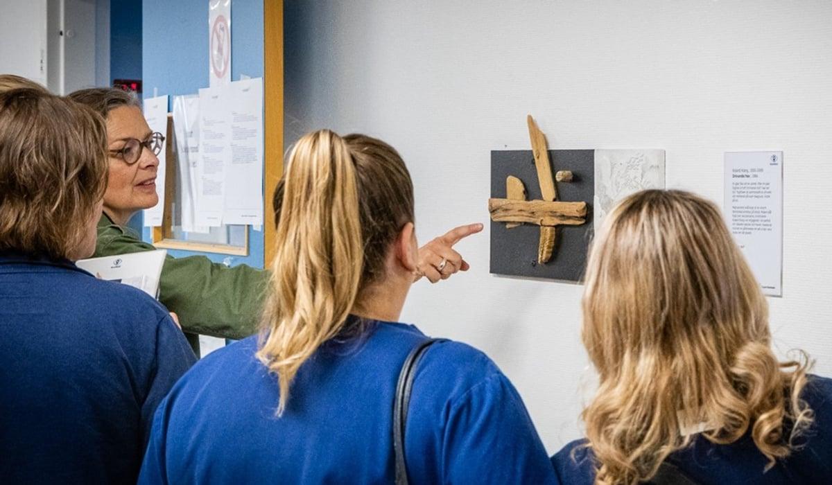En person pekar på konst på väggen framför en grupp av vårdpersonal.