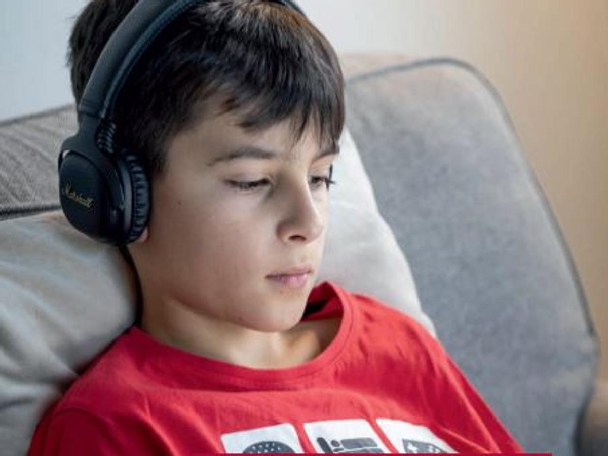 Pojke med hörlurar sitter i en soffa
