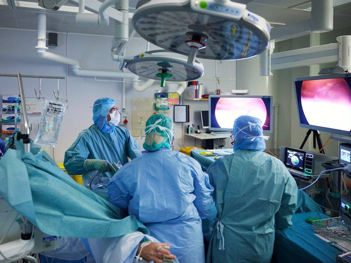 Bild från en operationssal där en laparoskopi pågår. Tre sjukvårdspersonal arbetar med en patient.