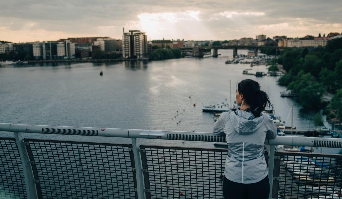 Kvinna på bro blickar ut över Stockholms vatten.