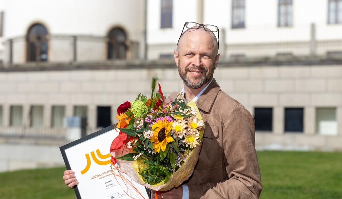 Foto på Finn Filén som håller i blommor och diplom