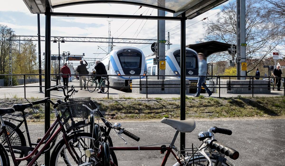 Folk som går mot pendeltåg från cykelparkering och busshållplats