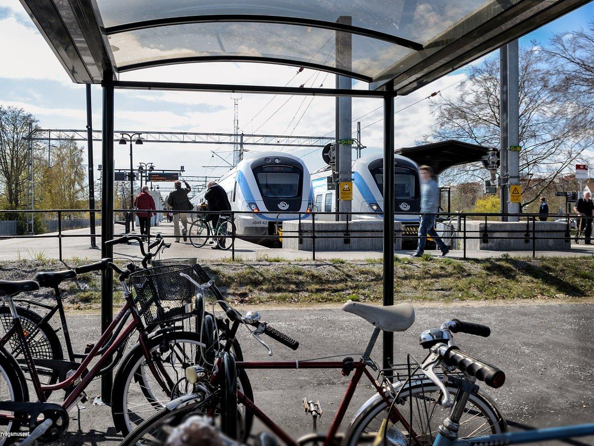 Folk som går mot pendeltåg från cykelparkering och busshållplats