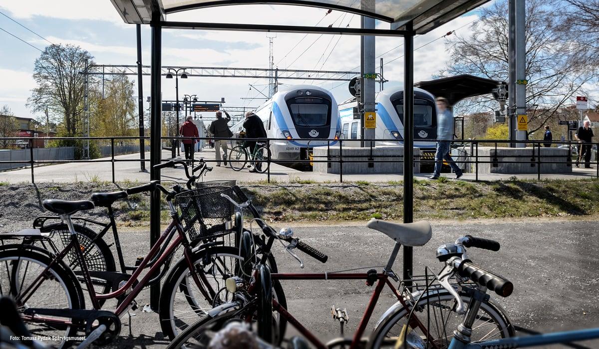 Folk som går mot pendeltåg från cykelparkering och busshållplats