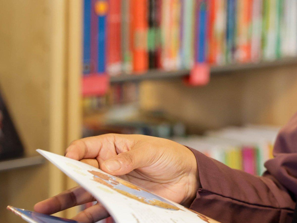 En bibliotekarie står och bläddrar i en bok