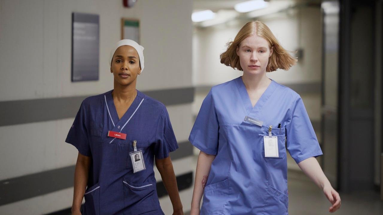 Två medarbetare inom sjukvården går igenom en korridor