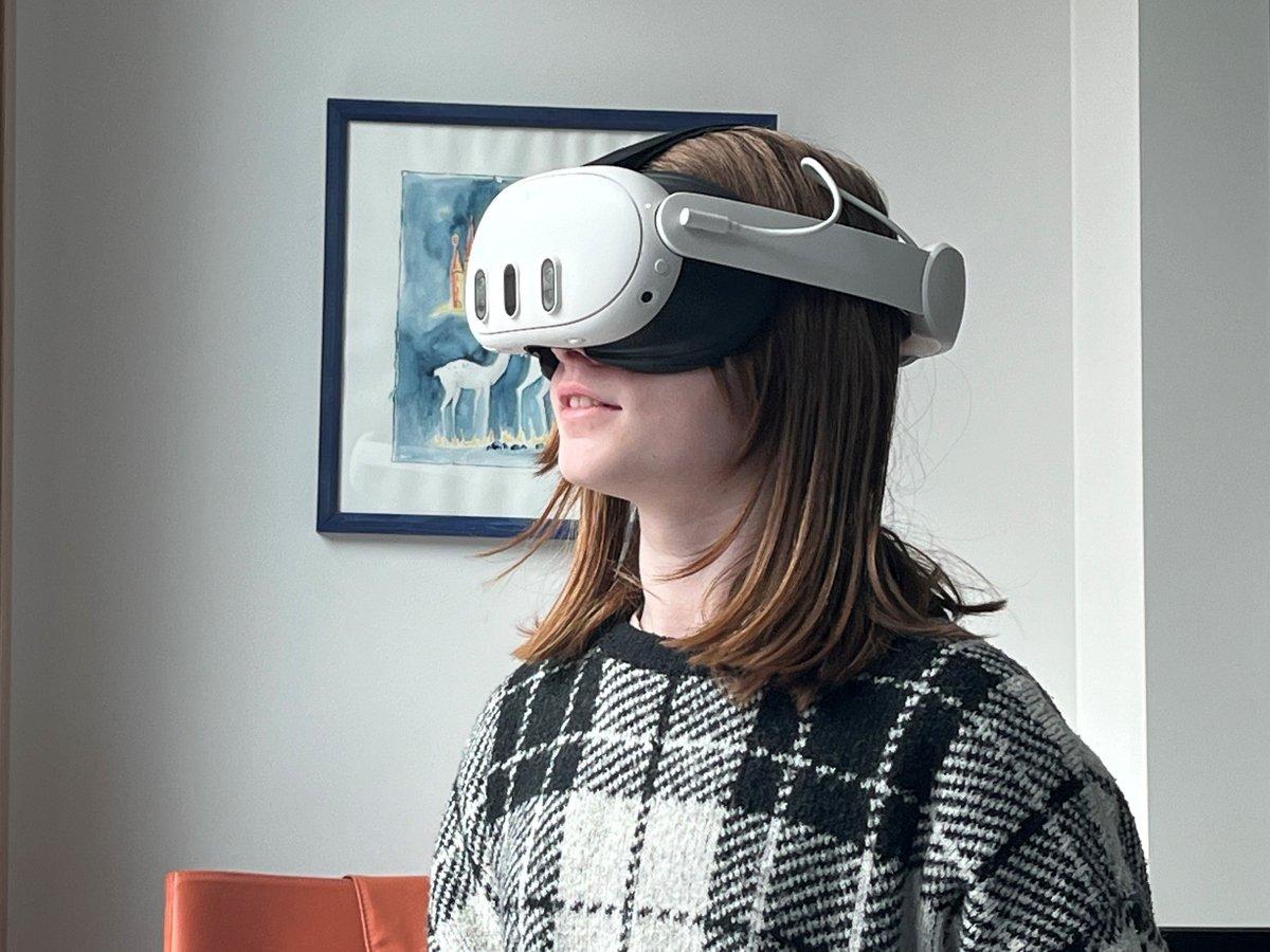 En flicka i 10-årsåldern står med VR-headset och handkontroller i ett sjukhusrum