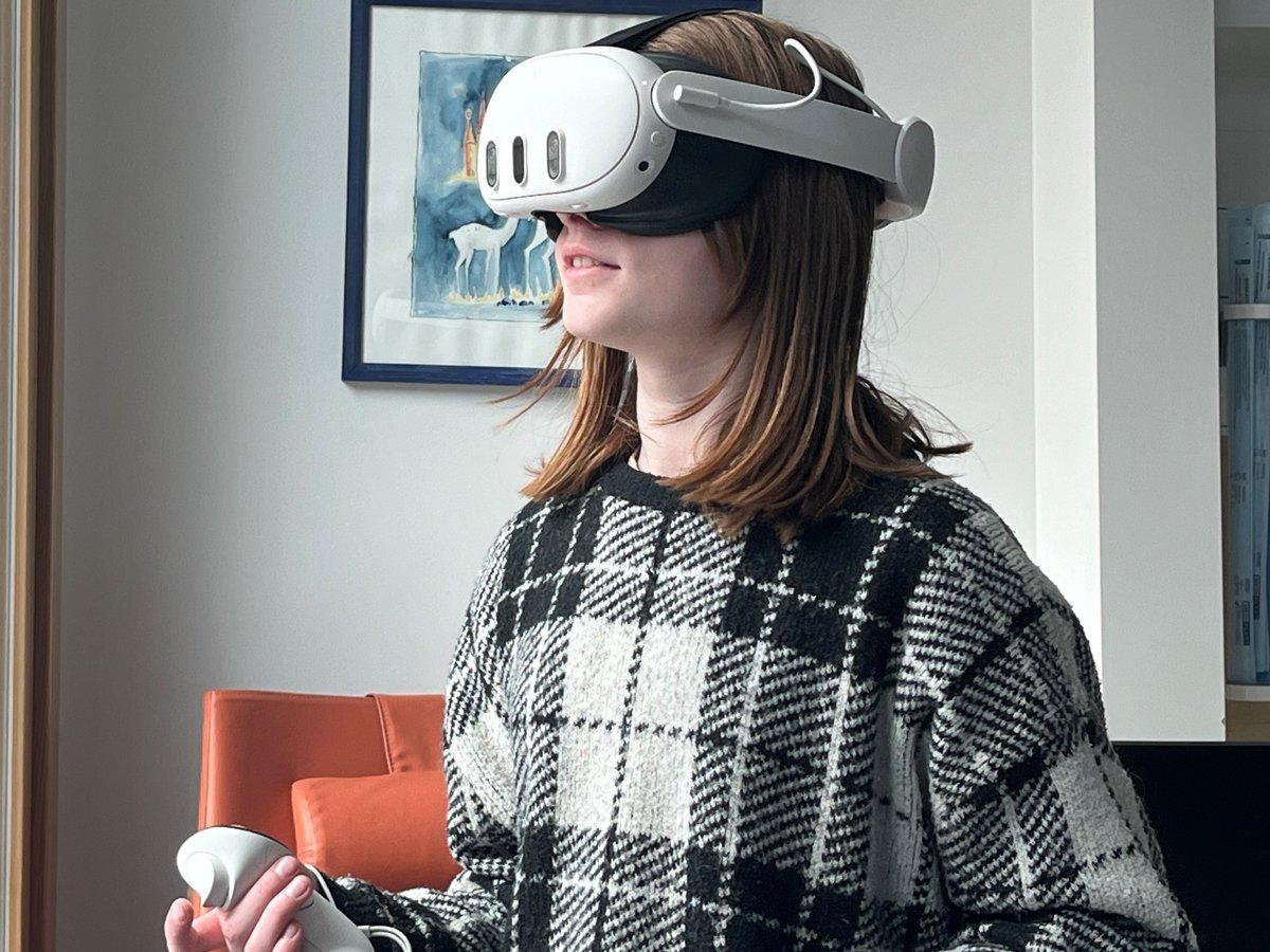 En flicka i 10-årsåldern står med VR-headset och handkontroller i ett sjukhusrum