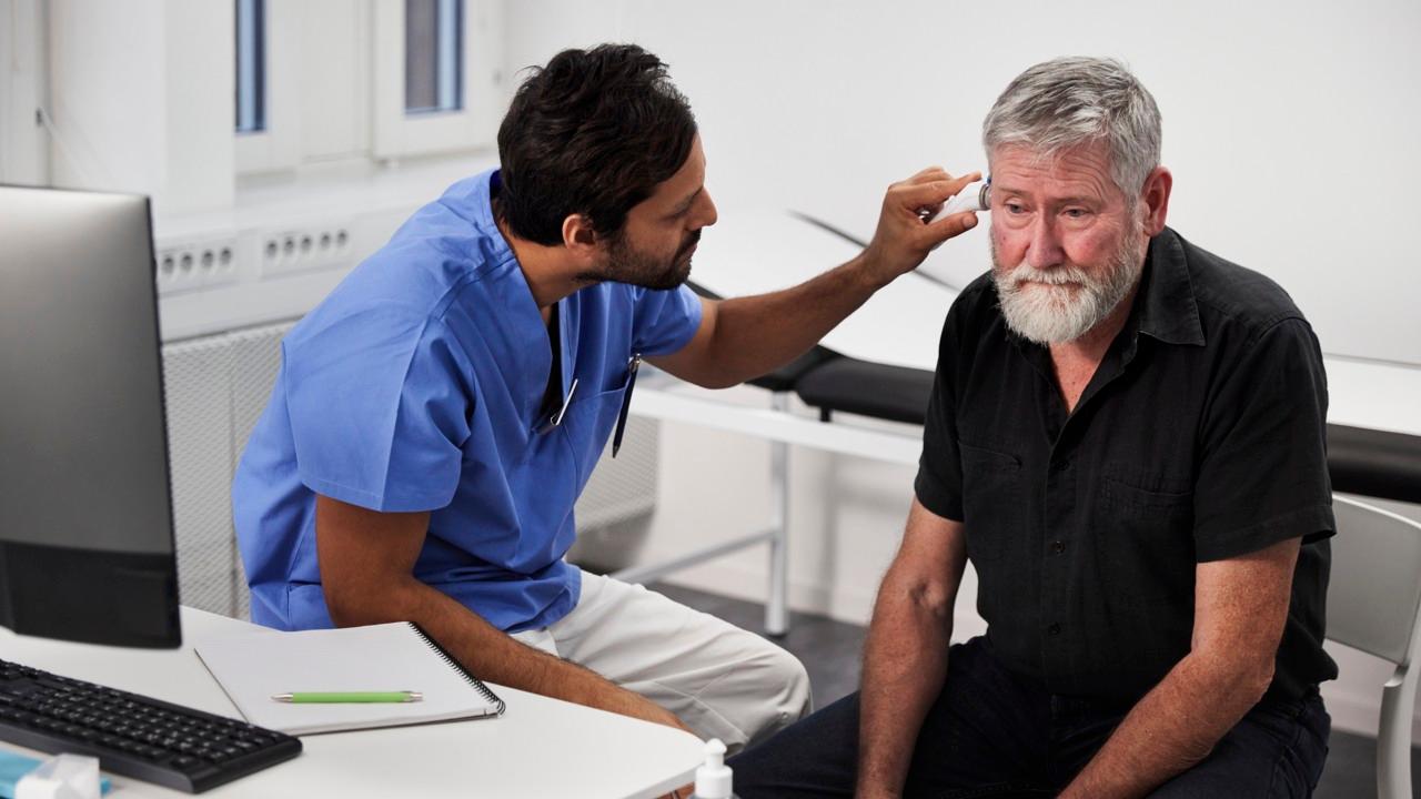 En medarbetare inom vården undersöker en äldre manlig patient