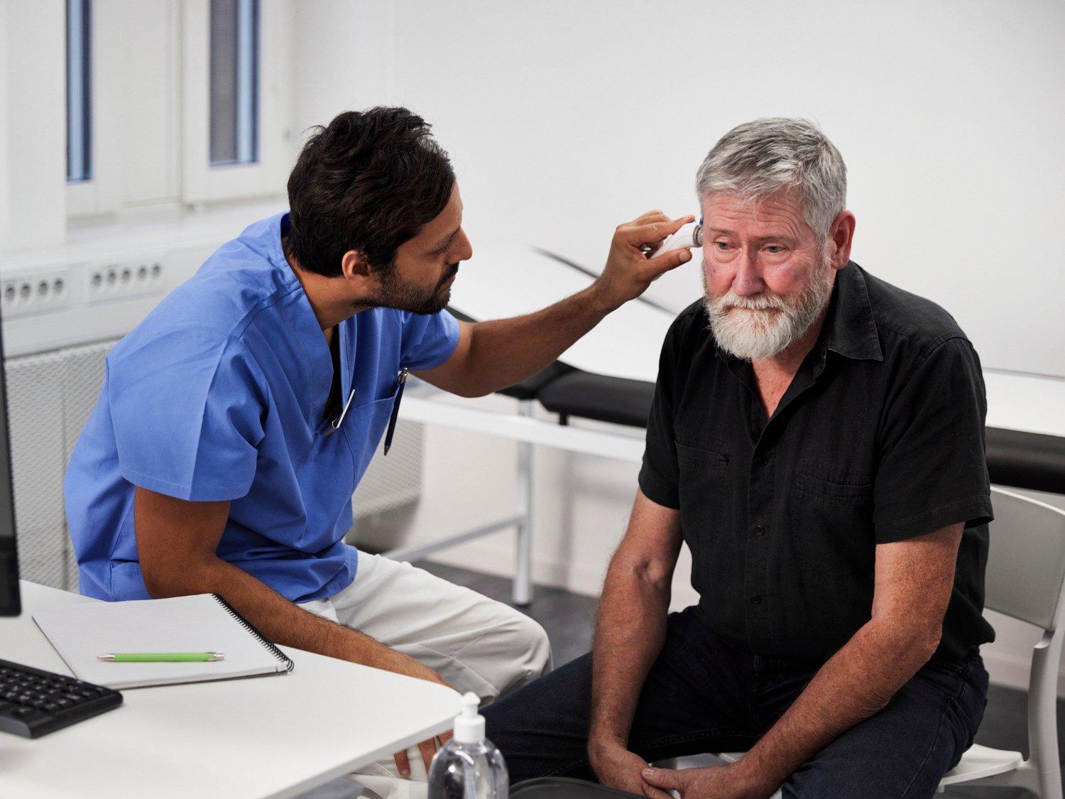 En läkare undersöker en äldre manlig patient
