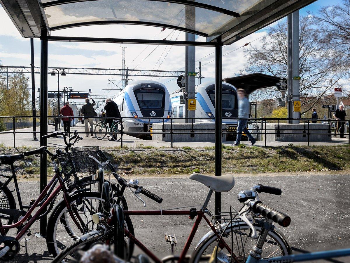 Folk som går mot pendeltåg från cykelparkering och busshållplats