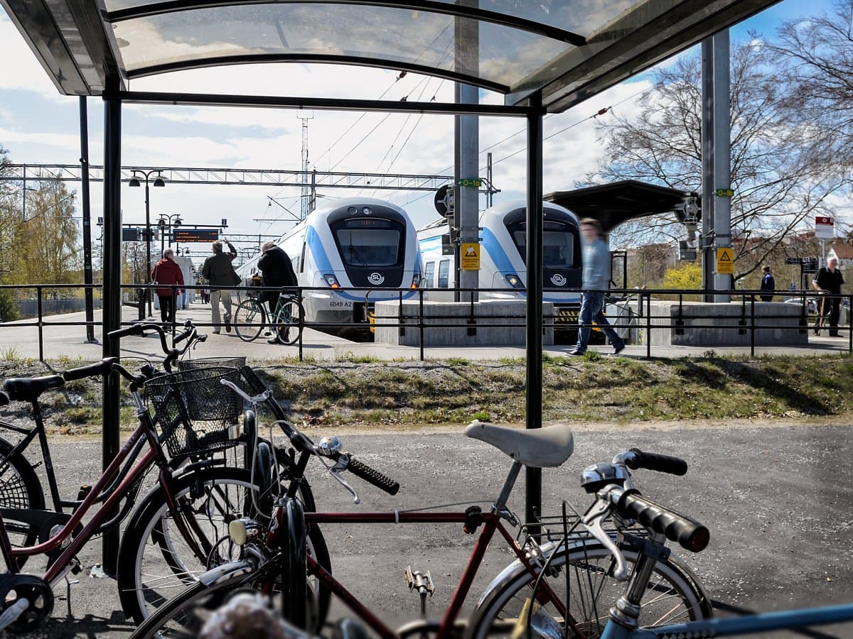 Folk som går mot pendeltåg från cykelparkering och busshållplats