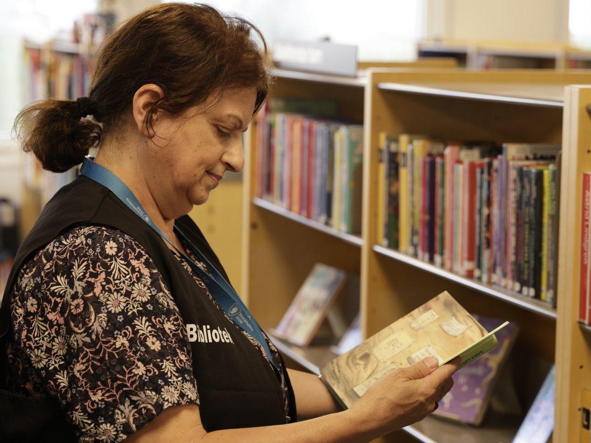 Bibliotekarie står och bläddrar i en bok