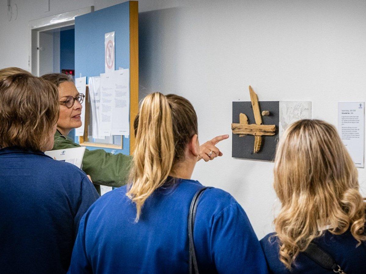 Cecilia pekar på ett konstverk framför en grupp ur personalen.