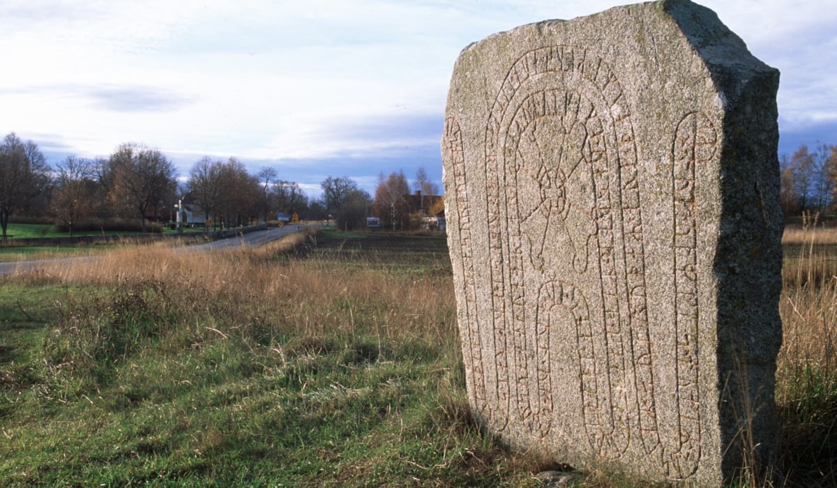Landskapsbild med en runsten i förgrunden.