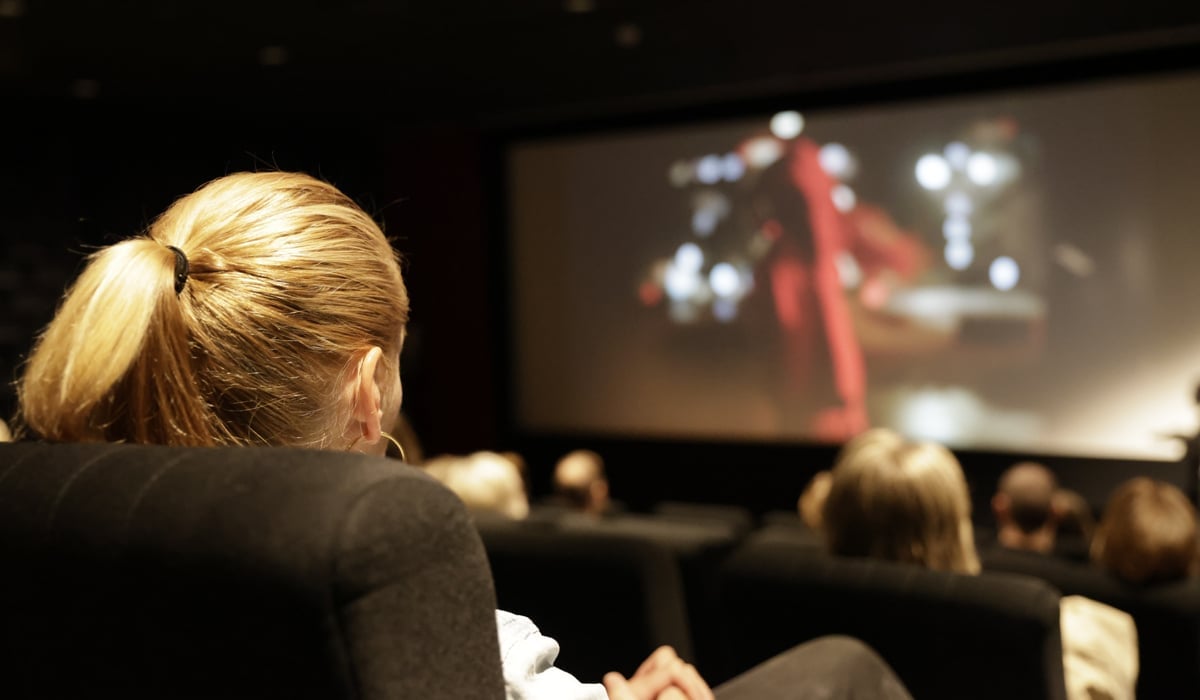 Personer som sitter i en biografsalong och tittar på film
