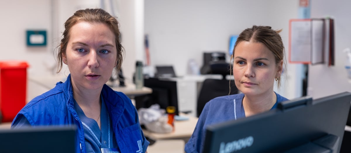 Två kvinnor sitter framför datorer.