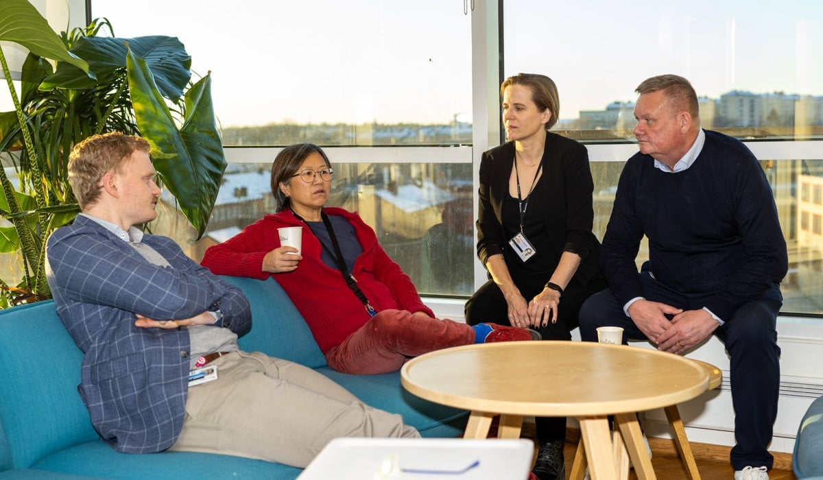 Fyra personer sitter kring ett bord och pratar.