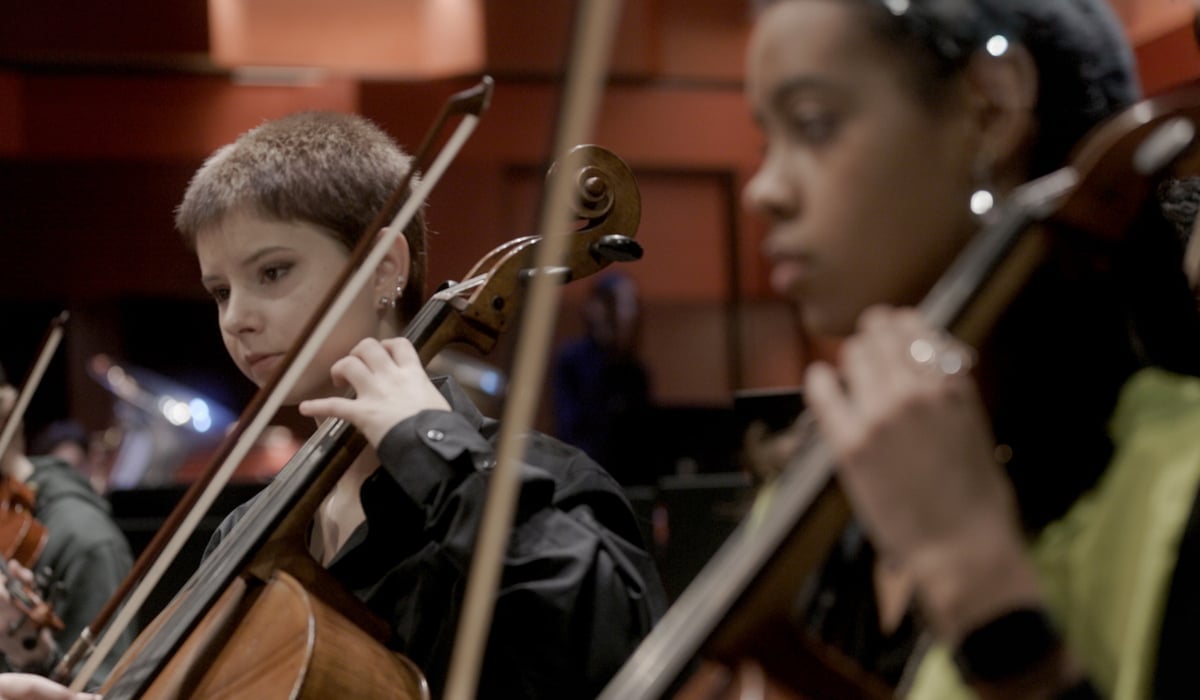Två ungdomar spelar musik i en stor sal